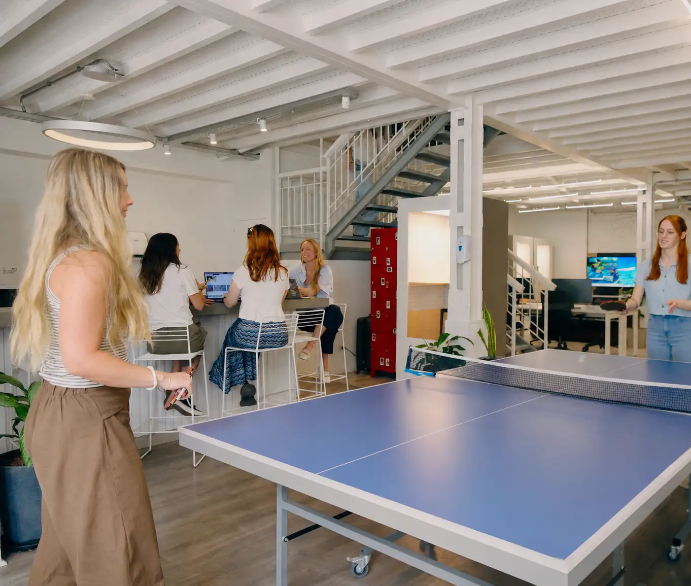 Engineers playing ping-pong and working together at a Howdy House